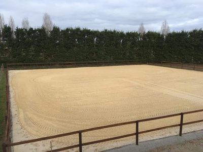 La carrière extérieure fraîchement hersée, bordée de haies